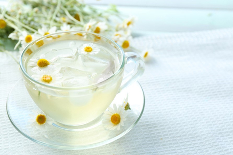 En kop kamille te med isterninger og kamilleblomster i.